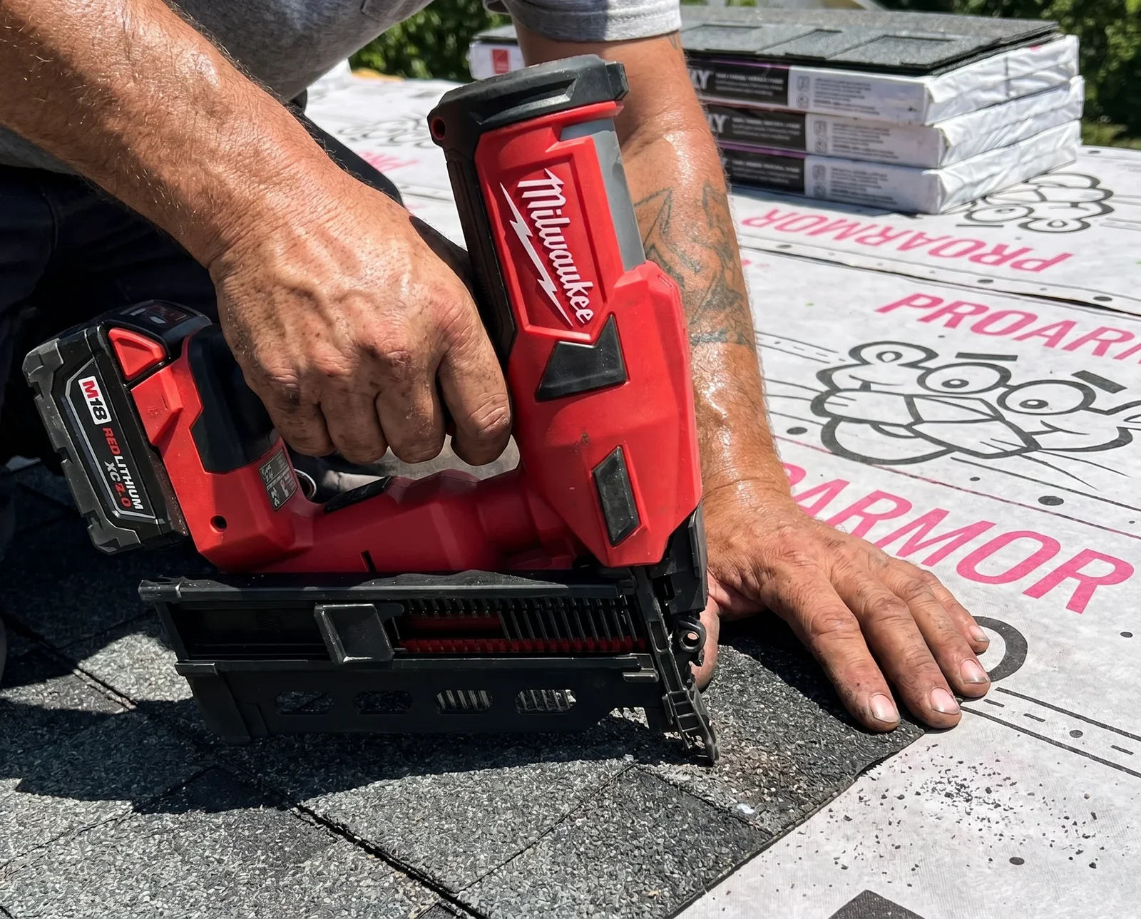 Hands using a cordless nail gun on roofing material