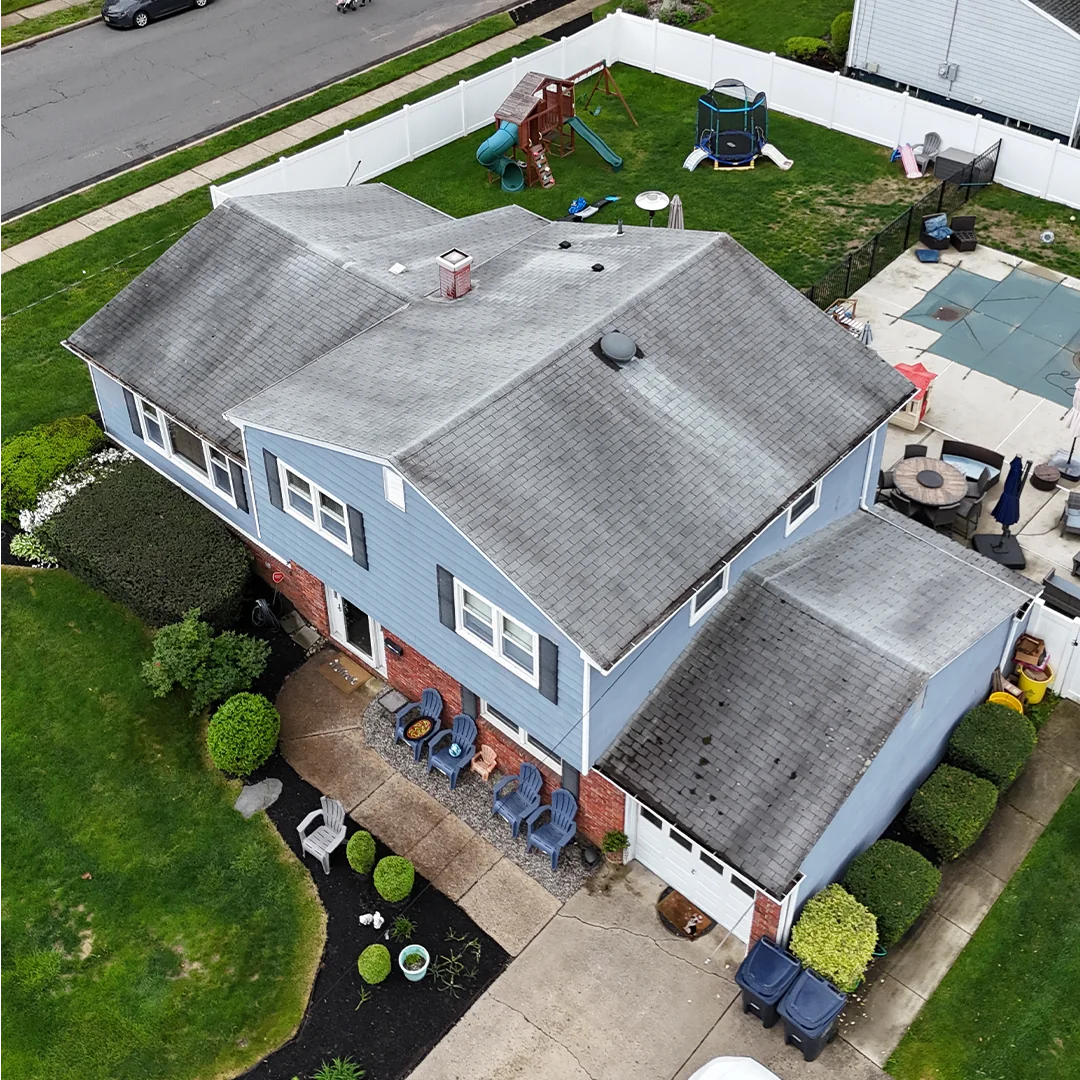 Aerial view of a two-story house with a worn gray shingle roof