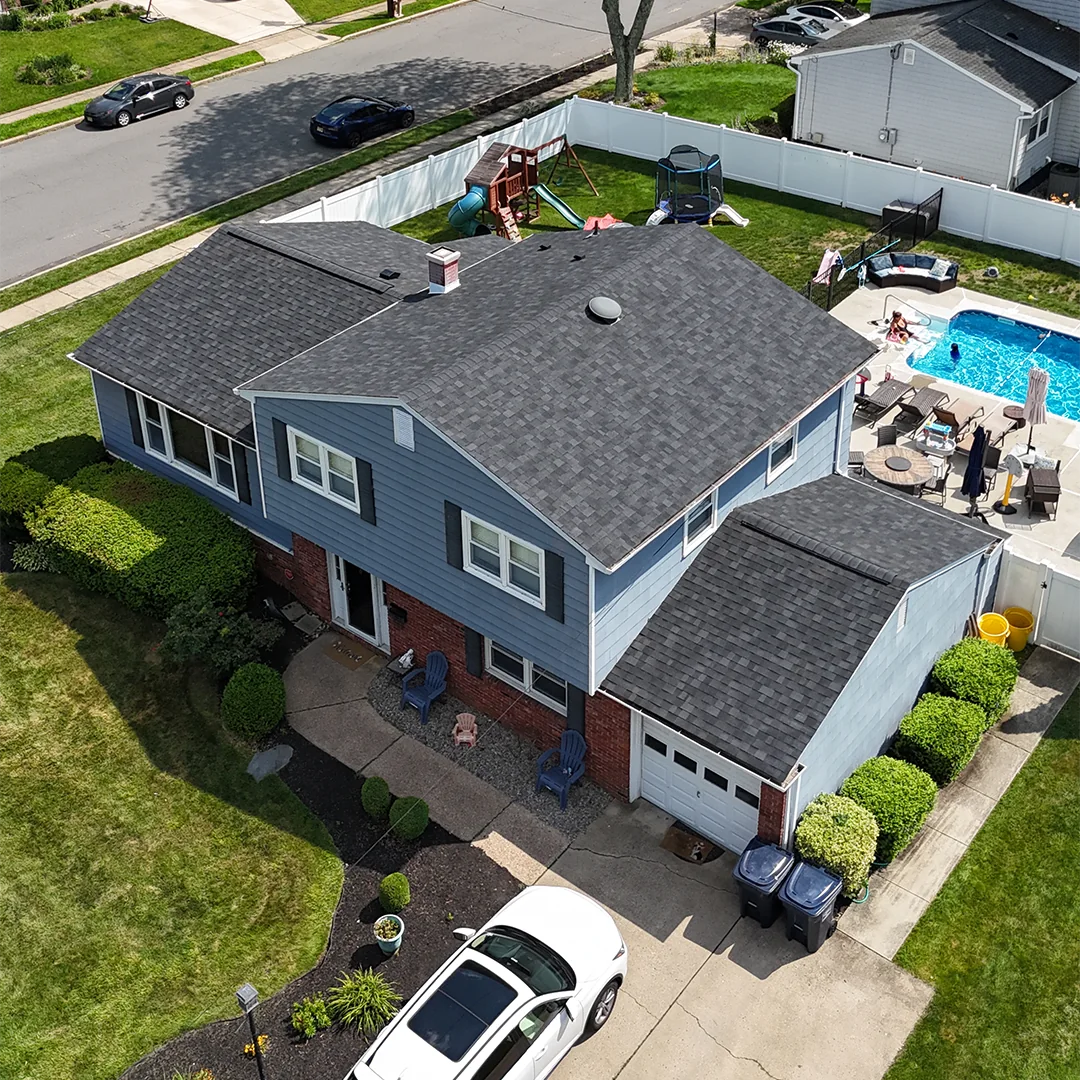 Aerial view of a two-story house with a dark shingle roof